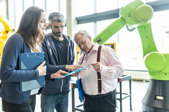 Technicians showing new industrial robot to senior colleague