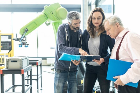 Technicians showing new industrial robot to senior colleague
