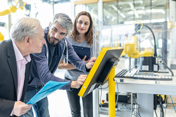 Technicians in industrail factory explaining control panel to senior manager
