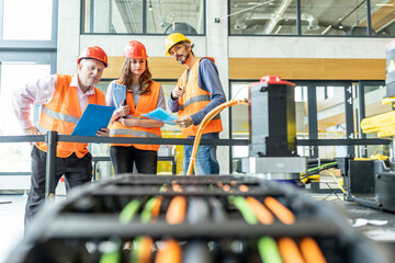 Enineers in factory examining work machine
