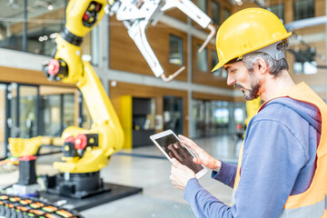 Skilled worker controlling robot arm with digital tablet