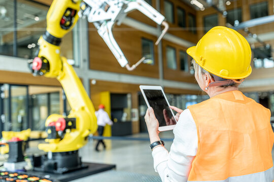 Skilled worker controlling robot arm with digital tablet