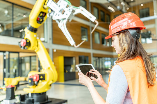 Skilled worker controlling robot arm with digital tablet