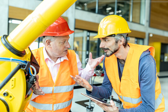 Male and female colleagues discussing robotic machine in industrial factory
