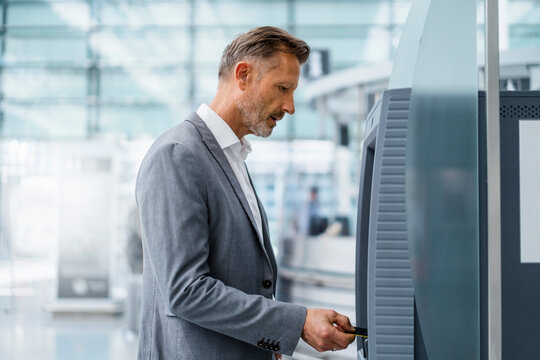 Mature businessman inserting credit card in ATM machine