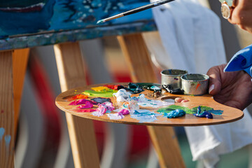 Hand of painter holding palette with oil colors