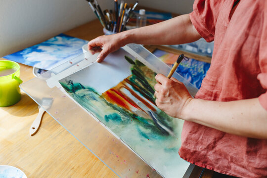 Artist with paintbrush painting on paper
