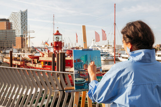 Artist painting at harbor on sunny day