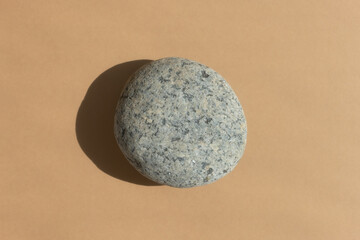 Podium made of natural gray stone on a beige background. Scene for product promotion, beauty, natural eco cosmetic. Showcase, display case. Top view