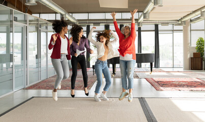 Cheerful businesswomen jumping together in office