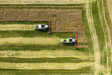 Fototapeta na wymiar aerial view over modern heavy harvesters remove the ripe wheat bread in field. Seasonal agricultural work