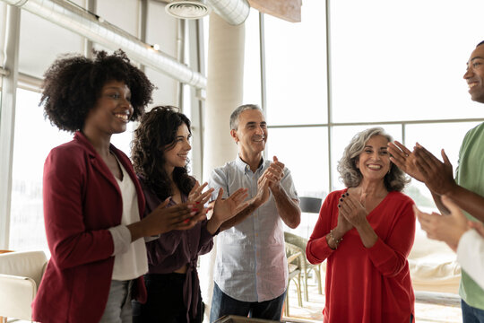 Happy businesswoman and businessmen clapping in office