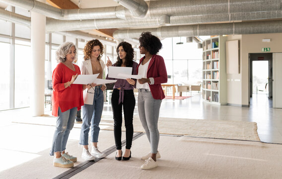 Businesswoman discussing over documents with colleagues in office