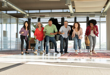 Happy businessmen and businesswomen running together in office