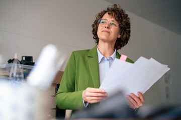 Thoughtful businesswoman with documents in office