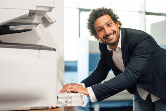 Smiling businessman using computer printer at office