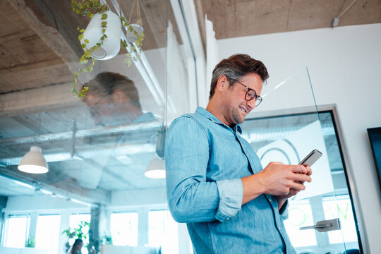 Smiling businessman using smart phone in office