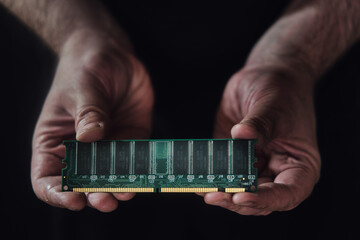 Computer board with a ram memory chip in the hands of a man on a black background