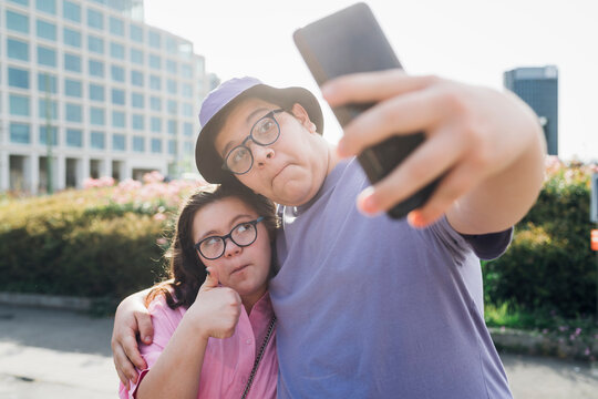 Teenage girl and boy making faces and taking selfie through mobile phone