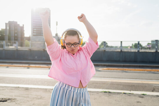 Teenage girl wearing headphones and dancing on street