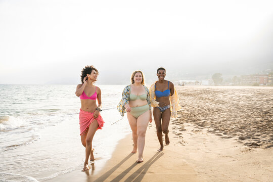 Multiracial women walking at beach on sunny day
