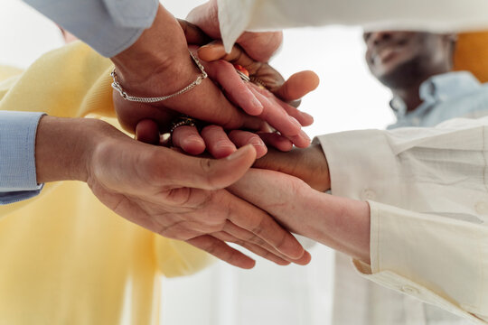 Colleagues stacking hands together in team building training
