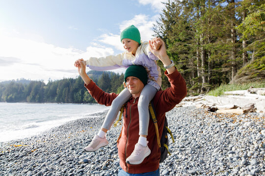 Father carrying daughter on shoulders at beach
