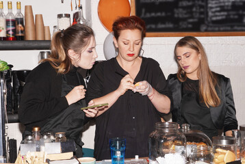 Experienced smiling middle aged woman owner of a cafe giving master class. Coffee Shop, Bar, Counter, Cafe Concept. Young entrepreneur concept. Halloween bakering. Preparing for Halloween party.