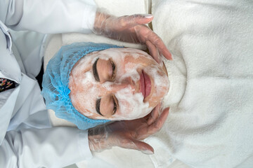 Obraz na płótnie Canvas cosmetologist performing ultrasonic cleaning and rejuvenation of woman's face in a spa center.