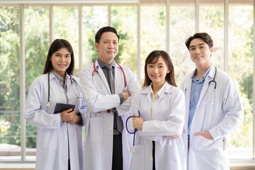 Group of Asian doctors team portrait standing with colleagues in background.