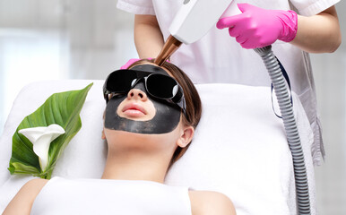 Carbon peeling procedure to beautiful blue-eyed girl in a beauty salon. Hardware cosmetology...