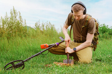 metal detector at work in the forest or field. Search for treasure and ancient values. Archeology. Man with a metal detector. Minesweeper Image