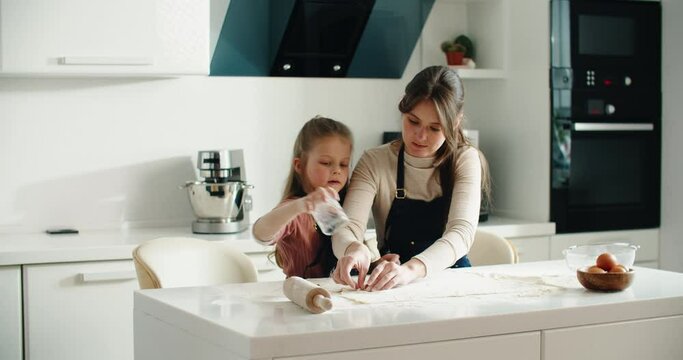 Mom teaches her daughter how to bake cookies at home. Form for baking. cooking. High quality 4k footage