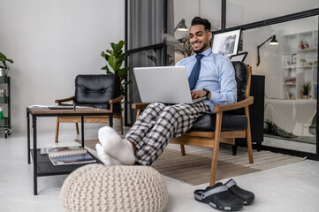Man working on laptop sitting in chair at home