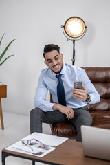 Confident man smiling looking at smartphone