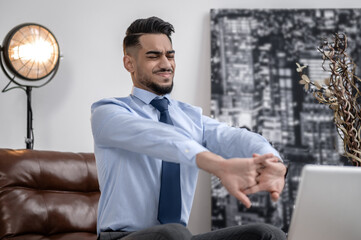 Man with closed eyes stretching in chair