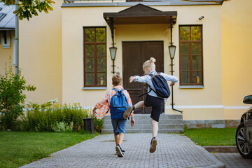 Fototapeta premium children running to school with backpacks on sunny day. Begining of academic year. Boys by school doorstep