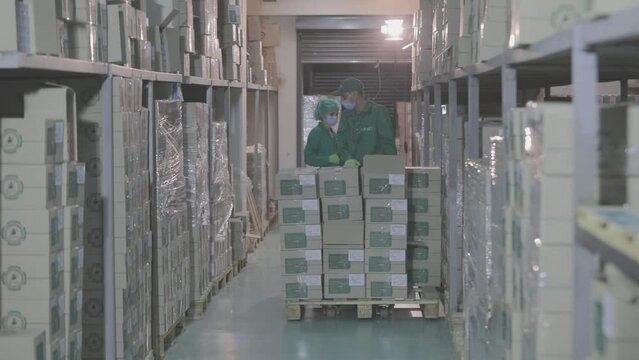 Workers in a warehouse wearing masks. Masked people in a modern warehouse. Warehouse at a pharmaceutical factory