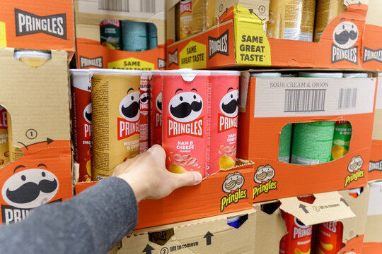 Tyumen, Russia-May 08, 2022: Hand hold a new tube of Pringles Potato Chips. Pringles is a brand of potato snack chips owned by the Kellogg Company