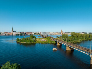 A bridge over river Daugava in Riga with a train passing by. Bridges in Latvia. Aerial Riga view.