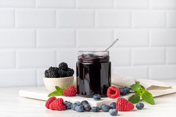 Berries jam in glass jar at white table. preserves for winter