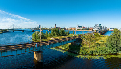 Naklejka premium A bridge over river Daugava in Riga with a train passing by. Bridges in Latvia. Aerial Riga view.