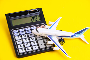 Airplane model and calculator yellow background.Concept of costs or expenses for air travel.Budget of trip.