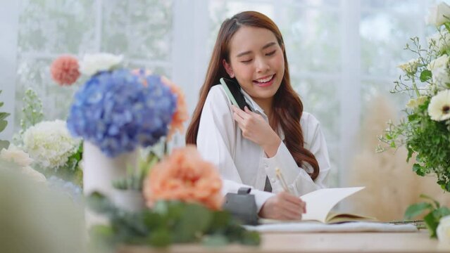 Small business,business online and New market concept.Young florist female use smartphone take photo bouquet of flower send to customer at workplace.woman artist working in flower shop studio at home