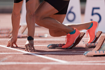 Man in a start block on an athletic track. A sprinter in a track and field race is poised at the...