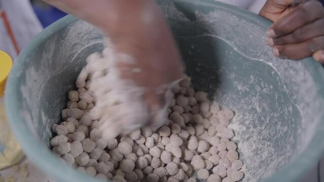 Coating battered groundnuts or peanuts in a dry mixture before frying - isolated close up