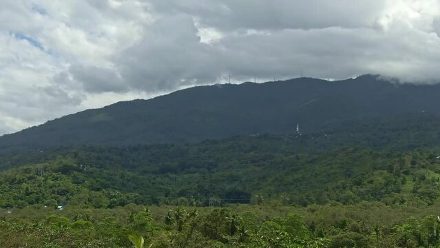 Natural nature view, calming shot of green silhouetted mountain, wind mill at the top and darkened cloud above