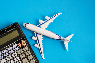 Airplane model and calculator blue background.Concept of costs or expenses for air travel.Budget of trip.