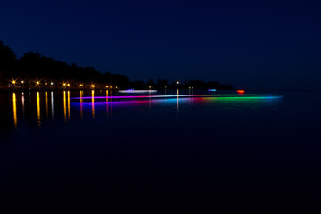 Beautiful long-exposure shot of a boat with RGB LEDs on its side at night