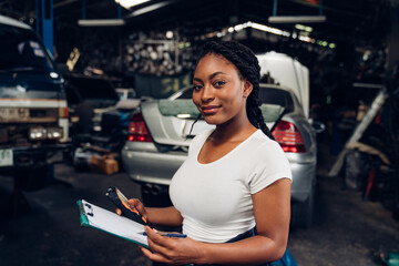 Portrait of woman auto mechanic holding clipboard at the repair garage. Repair service.